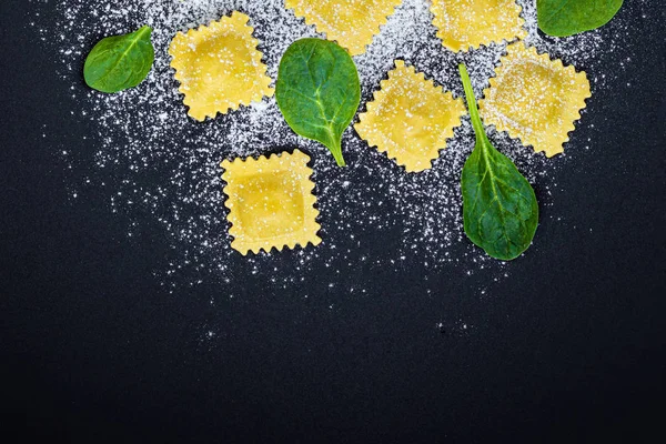 Fresh ravioli pasta with Spinach leaves, flour and herbs on blac — Stock Photo, Image