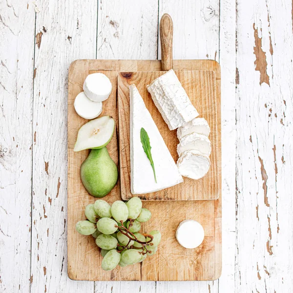 Tabla de quesos con diferentes quesos, peras y uvas en blanco w — Foto de Stock