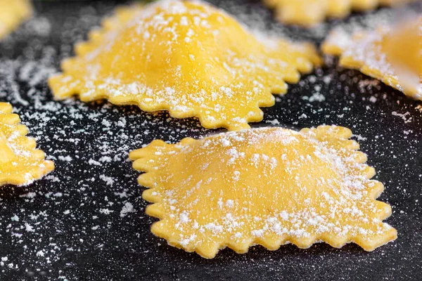 Raviolli with flour and herbs on black background, close up.  It — Stock Photo, Image