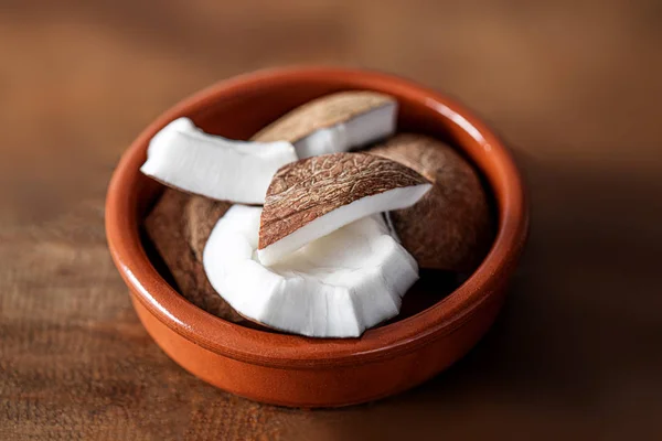 Trozos de coco en un tazón de cerámica sobre fondo de madera, parte superior vi — Foto de Stock