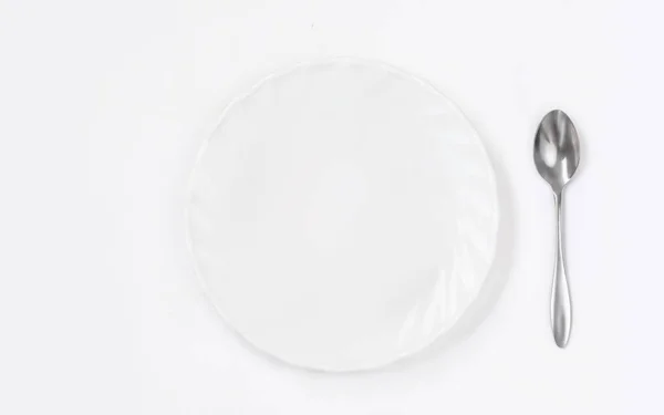 Okrągły biały talerz z łyżką na białym tle widok z góry. Płaskie — Zdjęcie stockowe