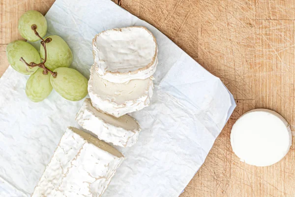 Prato de queijo com diferentes queijos e uvas em madeira branca — Fotografia de Stock