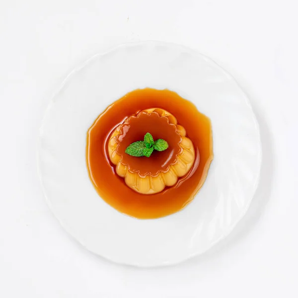Карамельный десерт на тарелке со сладким карамельным сиропом — стоковое фото