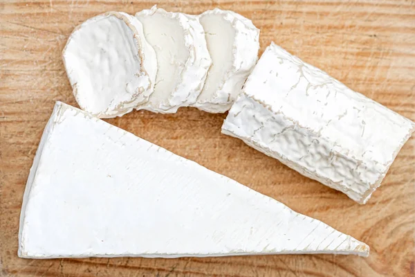 Dřevěná deska s bílým kozím sýrem na světlých pozadí. Sýr — Stock fotografie