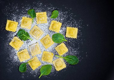 Siyah arka planda un ve ıspanak ile Ham Ravioli. İtalyanca