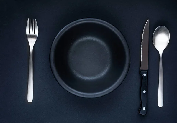 Black plate  on a black Background, top view. Dark Table setting Stock Picture