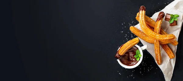 Churros con una taza de chocolate caliente sobre fondo negro. Top vie — Foto de Stock