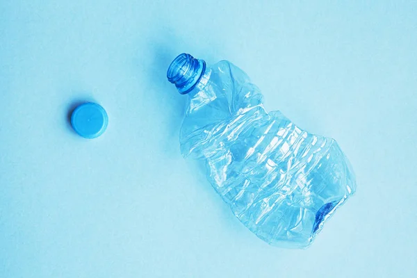 used plastic bottle with cap on blue background, flat lay, top view