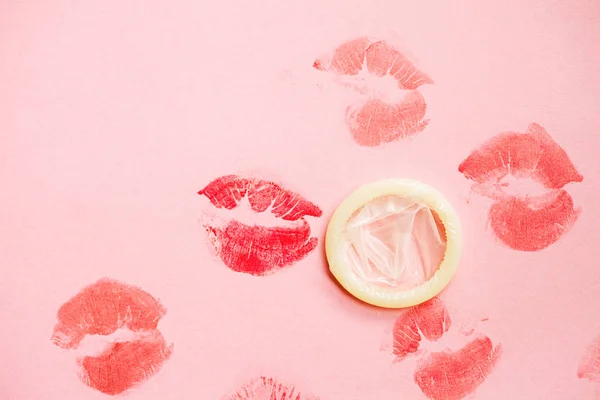 white condom isolated and lipstick kisses on pink background, safe sex, love affair