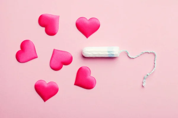 clean cotton tampon and red hearts on pink background