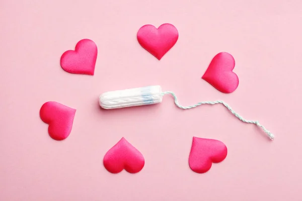 clean cotton tampon and red hearts on pink background