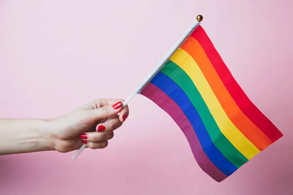 female hand waves gay pride LGBT rainbow flag