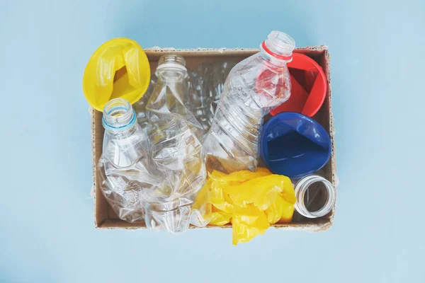 waste management, clean plastic water bottles, cups and bags ready for recycling on blue background, top view, flat layout