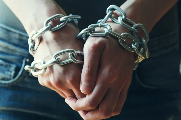young woman\'s hands tied up with chains
