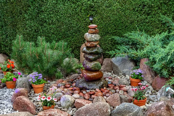Fountain in the yard is made of stones and  illuminated by lamps