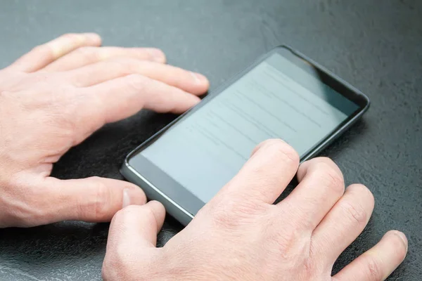 Man reads news on his mobile phone, which lies on the table