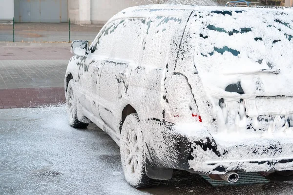 Черный автомобиль покрыт пеной на автомойке самообслуживания. — стоковое фото