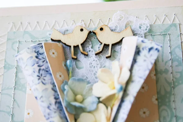 Handmade postcard in scrapbooking style. Two wooden birds looking at each other, lace, hand stitching, paper flowers