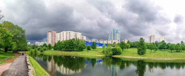 Un rincón verde de tranquilidad con árboles, césped, estanque, ubicado entre zonas residenciales urbanas en un día nublado. Pequeño parque familiar en las afueras de Moscú, Rusia — Foto de Stock