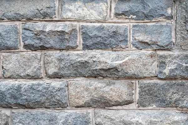 Una pared de ladrillos de granito áspero con lechada de cemento entre ellos —  Fotos de Stock