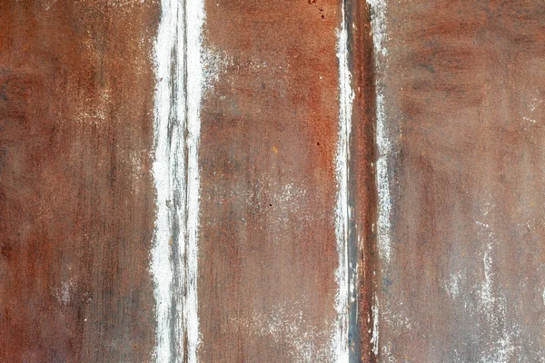 Rusty and red metal garage wall with brushstrokes of white paint and vertical stripes