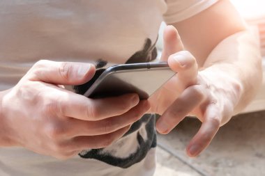 Sağdan düşen güneş ışığı açık havada bir cep telefonu ile erkek ellerin Closeup görünümü