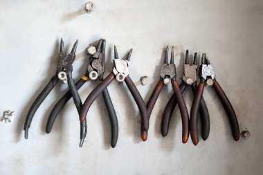 Atölyede kirli beyaz bir duvarüzerinde metal tutucular asılı yuvarlak pliers bir dizi