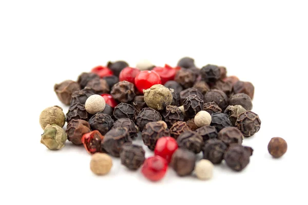 A mix of four types of pepper grain: black, white, pink, green. Isolated on white background. Selective focus. Closeup view — Stock Photo, Image