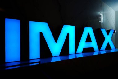 Blue neon inscription IMAX in front of the entrance to the third hall of the cinema clipart