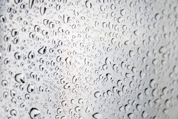 Gotas de água no vidro contra um fundo turvo turvo do céu em um dia chuvoso. Foco seletivo — Fotografia de Stock