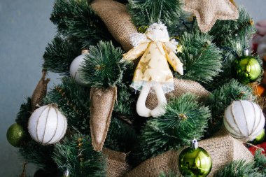 Beyaz ve yeşil toplar, çuval bezi oyuncaklar ve bir melek oyuncak ile dekore rustik tarzıyapay Noel ağacı,