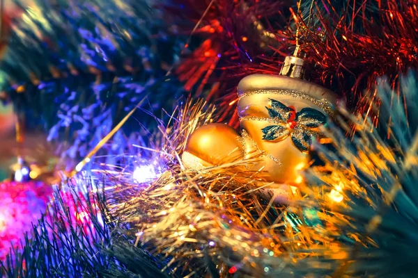 Golden boot toy hanging on a Christmas tree among the shiny garlands