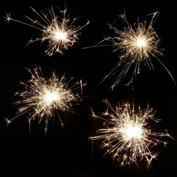 Set of four bright burning sparklers on a black background — Stock Photo, Image