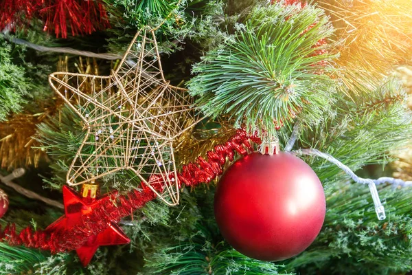 Arbre de Noël artificiel vert décoré d'une étoile dans un cadre doré et entrelacant des fils dorés ; boule rouge mat ; et guirlandes jaunes et rouges. Décoration de maison pour des vacances en famille. Concentration sélective — Photo