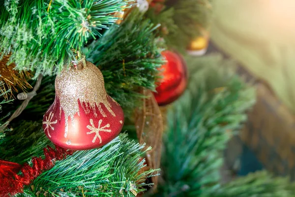 Zelený umělý vánoční stromek zdobený červeným zvonkem se zlatými třpyty a dalšími hračkami. Domácí dekorace pro rodinné svátky s prostorem pro kopírování. Selektivní zaměření — Stock fotografie