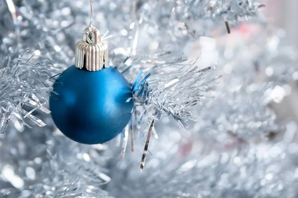 Closeup pohled na modrý matný míč zavěšený na stříbrném vánočním stromku. Selektivní zaměření. Rozmazané pozadí. Domácí dekorace pro rodinné svátky — Stock fotografie
