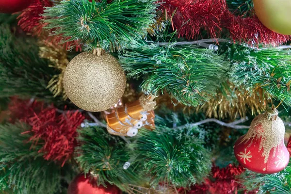 Arbre de Noël artificiel vert décoré d'une belle boule d'étincelle dorée, de guirlandes rouges et dorées et d'autres jouets. Concentration sélective — Photo