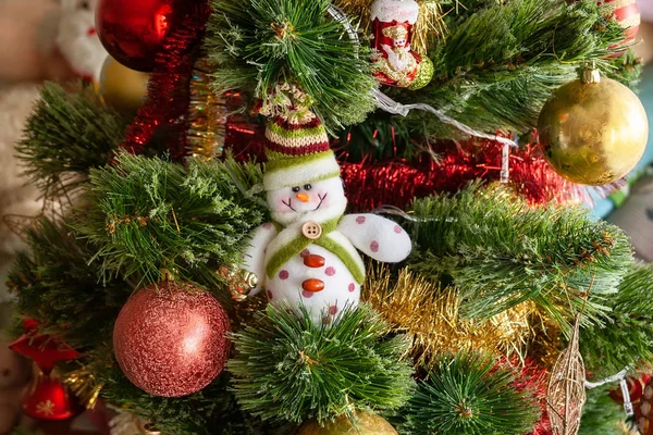 Arbre de Noël artificiel vert décoré de beaux bonhomme de neige souriant textile, guirlandes rouges et dorées et autres jouets. Décoration de maison pour des vacances en famille — Photo