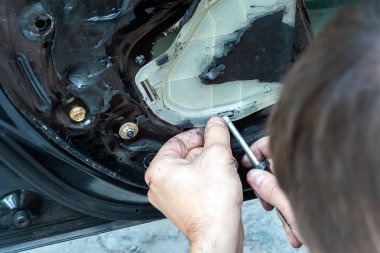 Bir adam bir güç penceresini onarmak için bir araba kapısını tornavidayla söker. Kalifiye bir işçi tarafından bir servis istasyonunda araba tamir. Hatalı bir arabada sorun aranıyor