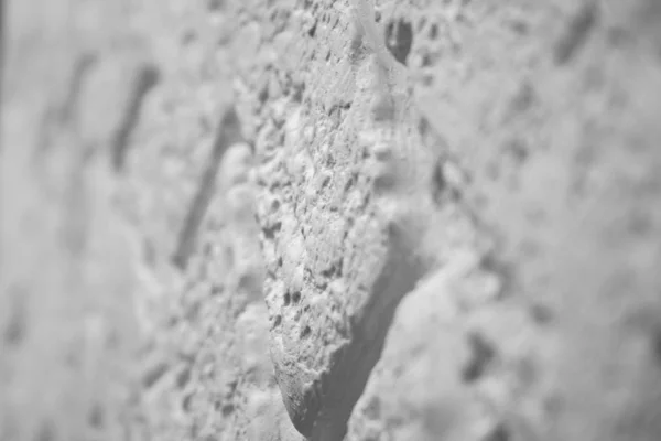 Closeup tilt shift view of a decorative rough white brick wall background. Selective focus