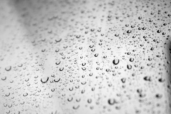Краплі води на скляному вікні на тлі розмитого сірого неба на дощовий осінній день. Вибірковий фокус — стокове фото