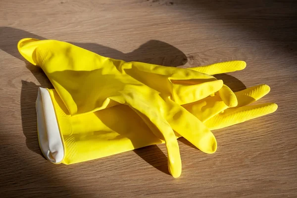 Žluté gumové rukavice pro domácí práce leží na dřevěném povrchu slunečného dne. Zobrazení closeup — Stock fotografie
