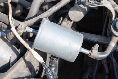 Yakıt tankına bağlı bir arabaya yüklenmiş bir yakıt filtresinin yakın çekim görüntüsü. Yakıt hattındaki filtre elementi benzindeki toz ve toz parçacıklarını hapsediyor.