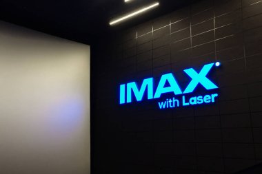 Sinema salonundaki büyük ekranın yanındaki siyah duvarda lazer olan mavi neon yazıtlar.