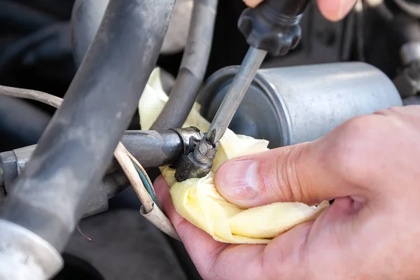 Mannelijke handen schroef de brandstofleiding uit het brandstoffilter met een Phillips schroevendraaier om het te vervangen. Reparatie en vervanging van auto-onderdelen in een servicecentrum. Close-upzicht — Stockfoto