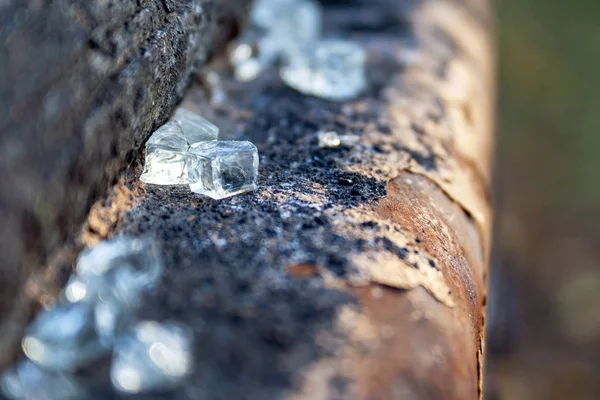 Closeup view of small glass shards lying on a rusty metal peeling pipe. Shattered, broken glass fragments. Selective focus. Blurred background — Stock Photo, Image