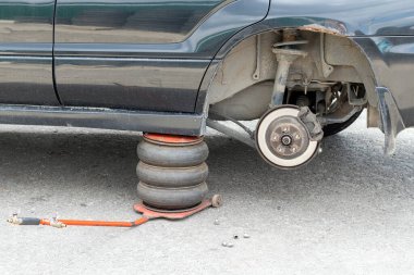 Lastik servis merkezinin direksiyonunu değiştiriyorum. Araba tamirhanesinde tekersiz, kirli siyah bir araba.