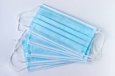 Beyaz arka planda mavi koruyucu tıbbi yüz maskeleri. Karantina, virüs, koronavirüs, hava kirliliği süresince solunum koruması
