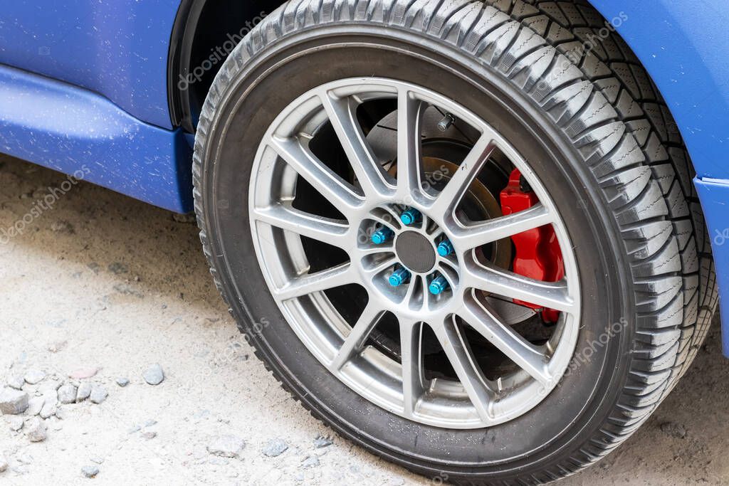 Stylish blue car wheel with red brake caliper and five-nut rim. Brake system support