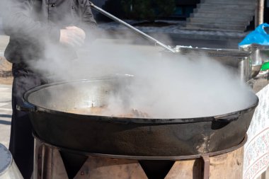Gerçek Özbek pilavı pişirmek. Geleneksel bir halk festivali sırasında dışarıda buharlı büyük bir kazanda kuzu pirzolası pişirmek.